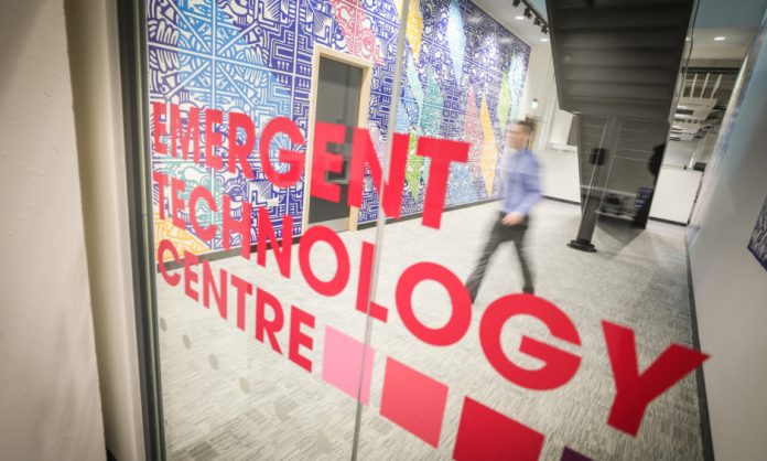 A close-up of a glass door in Abertay University, printed with the words Emergent Technology Centre.